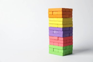Işık arka planında renkli bloklardan oluşan bir kule. Metin için boşluk