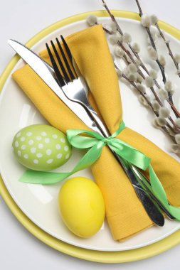 Paskalya kutlaması. Beyaz arka planda söğüt dalları ve boyanmış yumurtalar ile şölen masası, üst görünüm