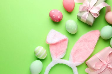 Boyalı Paskalya yumurtaları, tavşan kulaklıkları yeşil arka planda hediyeler, düz yatak. Metin için boşluk