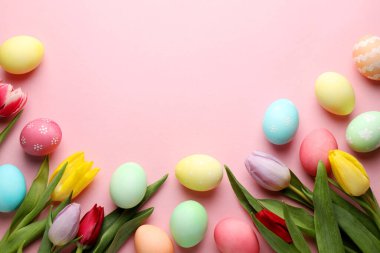 Boyalı Paskalya yumurtaları ve pembe arka planda güzel laleler. Metin için boşluk