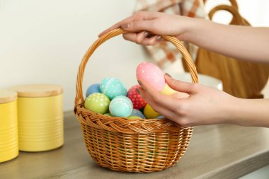 Paskalya sepetinde boyanmış yumurtalı bir kadın, kapalı masa, yakın plan.