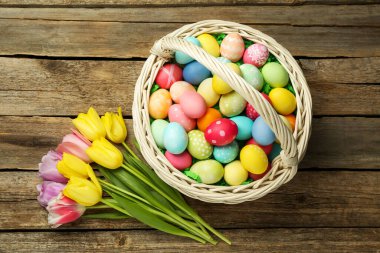Tahta masanın üzerinde boyanmış yumurtalar ve laleler olan Paskalya sepeti, düz yatıyordu.