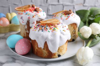 Lezzetli Paskalya pastaları, laleler ve beyaz mermer masaya boyanmış yumurtalar, yakın plan.