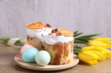 Lezzetli Paskalya pastaları, laleler ve ahşap masaya boyanmış yumurtalar. Gri arka plan, yakın plan.