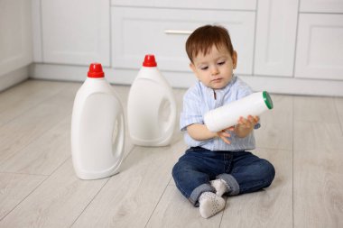 Evde çocuk güvenliği. Mutfakta temizlik malzemesi olan küçük bir çocuk.