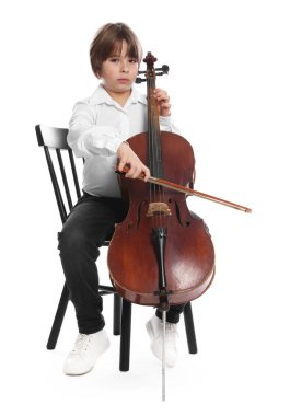 Küçük çocuk beyaz arka planda sandalyede keman çalıyor.