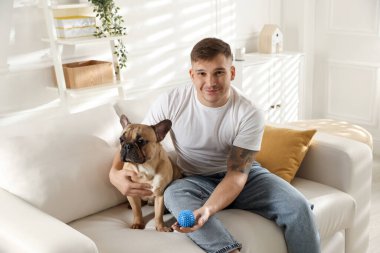 Evdeki kanepede dinlenen sevimli köpeğiyle genç bir adam.