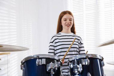 Davul çalmayı içeride öğrenen genç bir kız.