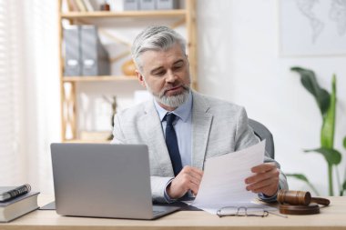 Takım elbiseli noter ofiste evrak işleriyle uğraşıyor.