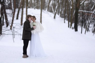 Mutlu yeni evli çift, bir buket çiçekle kış günü açık havada, mesaj atmak için yer var.