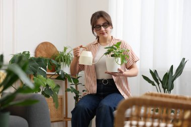 Evdeki çiçekleri sulayan güzel bir kadın.
