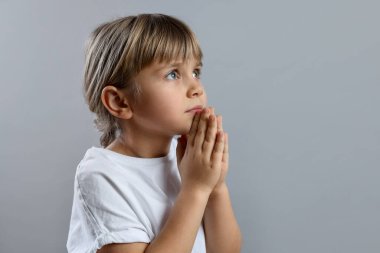 Açık gri arka planda dua eden küçük kız, mesaj için boşluk