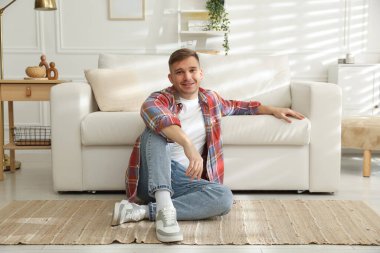 Evdeki kanepenin yanında dinlenen genç adam.