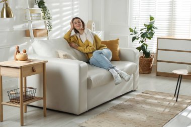 Mutlu kadın evdeki kanepede dinleniyor.