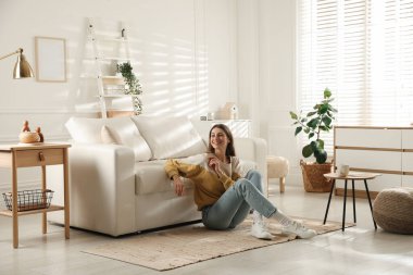 Evdeki koltuğun yanında dinlenen bir kadın.