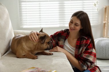 Evdeki kanepenin yanında sevimli köpeği olan bir kadın.