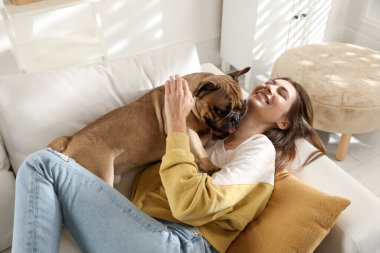 Evdeki kanepede tatlı köpeğiyle dinlenen bir kadın.