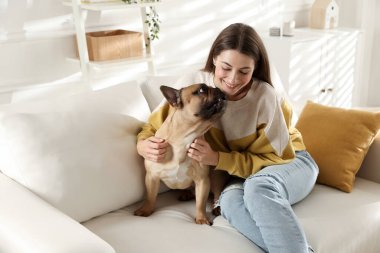 Evdeki kanepede tatlı köpeğiyle dinlenen bir kadın.
