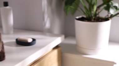 Banyoda gösteriş üzerine temiz havlu ve kozmetik ürünleri yığını, yakın çekim. Kamera sola hareket ediyor