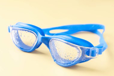 Sarı arka planda su damlaları olan yüzme gözlükleri, yakın plan