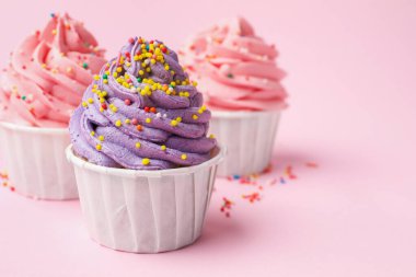 Pembe arka planda serpiştirilmiş lezzetli kekler, yakın plan. Metin için boşluk