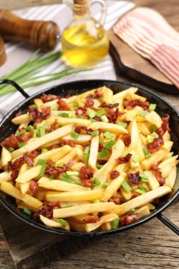 Pastırmalı patates kızartması ve ahşap masada yeşil soğan. Yakın plan.