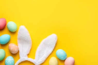 Mutlu Paskalyalar. Tatlı tavşan kulakları ve sarı arka planda boyanmış yumurtalar. Metin için boşluk