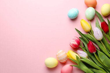 Boyalı Paskalya yumurtaları ve pembe arka planda güzel laleler. Metin için boşluk