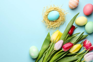 Boyanmış Paskalya yumurtaları ve açık mavi arka planda güzel laleler. Metin için boşluk