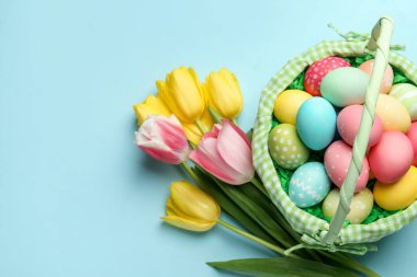 Açık mavi arka planda boyanmış yumurtaları olan Paskalya sepeti, düz yatıyordu. Metin için boşluk