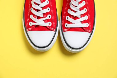 Sarı arka planda şık bir çift spor ayakkabı, üst manzara. Metin için boşluk