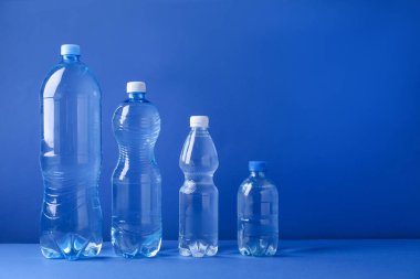 Mavi arka planda farklı boyutlarda su şişeleri var. Metin için boşluk