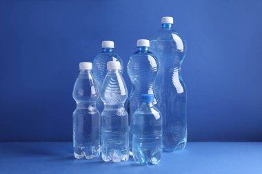 Mavi arka planda farklı boyutlarda su şişeleri