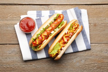 Ahşap masada soslu ve marullu lezzetli sosisliler.