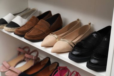 Ayakkabı deposu. İçerideki raflarda farklı ayakkabılar, yakın plan.