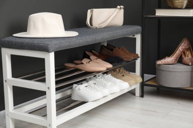 Gri duvarın yanında farklı ayakkabı ve aksesuarlarla ayakkabı deposu, yakın plan.