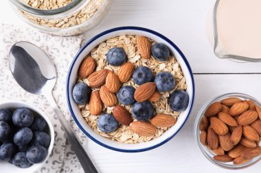 Yulaf gevreği, badem sütü, yaban mersini ve fındık beyaz ahşap masa, düz yatıyordu.