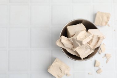 Tabaktaki taze maya parçaları beyaz fayanslı masada, düz yerde. Metin için boşluk