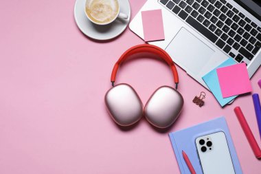 Kulaklık, akıllı telefon, dizüstü bilgisayar, pembe arka planda kahve ve kırtasiye malzemesi, düz yatak. Metin için boşluk