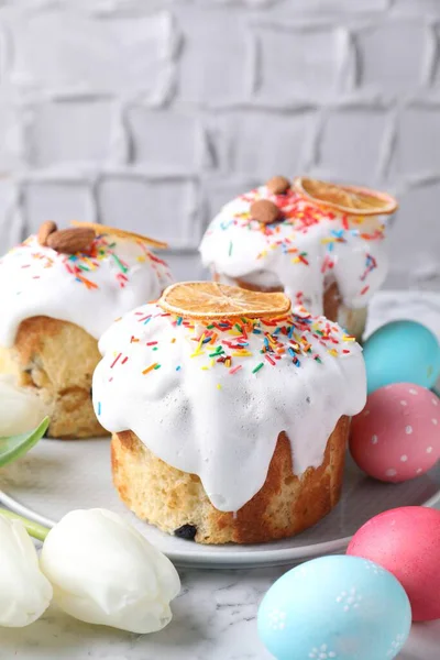 Lezzetli Paskalya pastaları, laleler ve beyaz mermer masaya boyanmış yumurtalar, yakın plan.