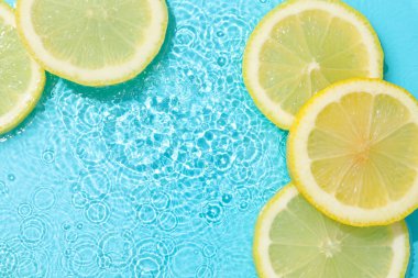 Açık mavi arka planda limon dilimleri, düz. Metin için boşluk