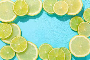 Açık mavi arka planda limon ve limon dilimleri, düz. Metin için boşluk