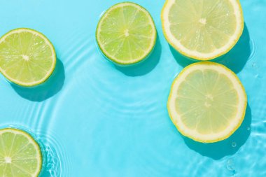 Açık mavi arka planda limon ve limon dilimleri, düz. Metin için boşluk