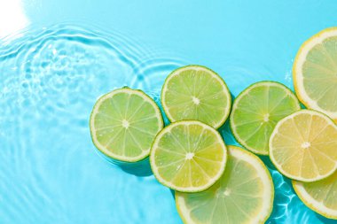 Açık mavi arka planda limon ve limon dilimleri, düz. Metin için boşluk