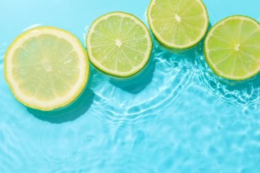 Açık mavi arka planda limon ve limon dilimleri, düz. Metin için boşluk