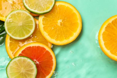 Turkuaz arka planda sudaki narenciye dilimleri, düzlük.