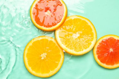 Turkuaz arka planda sudaki narenciye dilimleri, düzlük.