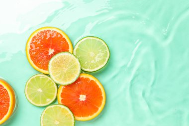 Turkuaz arka planda sudaki turunçgil meyveleri, düzlük. Metin için boşluk