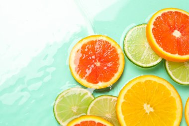 Turkuaz arka planda sudaki turunçgil meyveleri, düzlük. Metin için boşluk