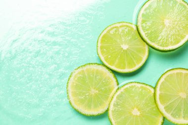 Turkuaz arka planda limon dilimleri, düz bir zemin. Metin için boşluk
